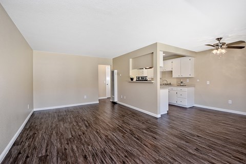 an empty living room and kitchen with a ceiling fan